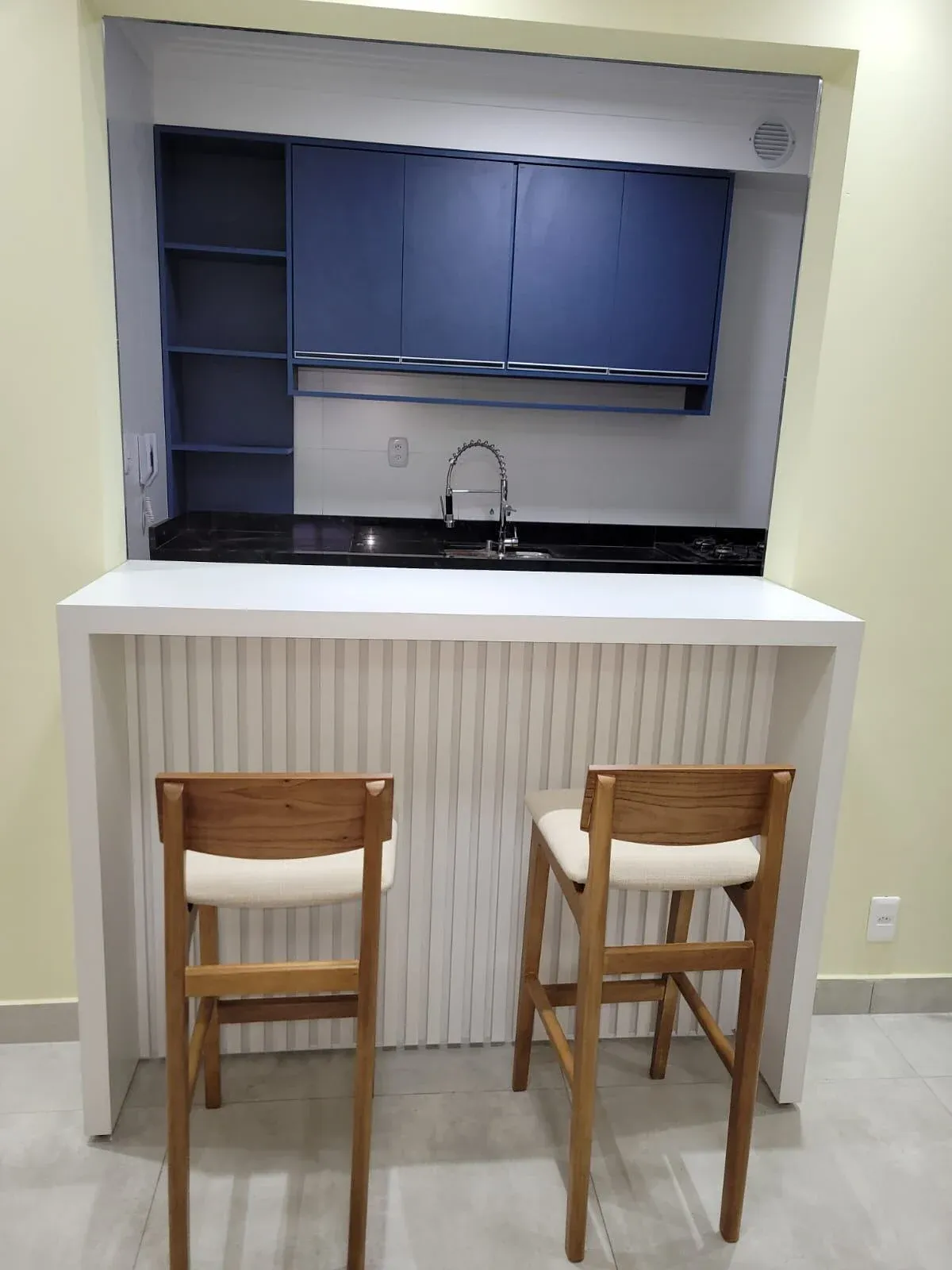 Bancada de refeições planejada com painel ripado e banquetas