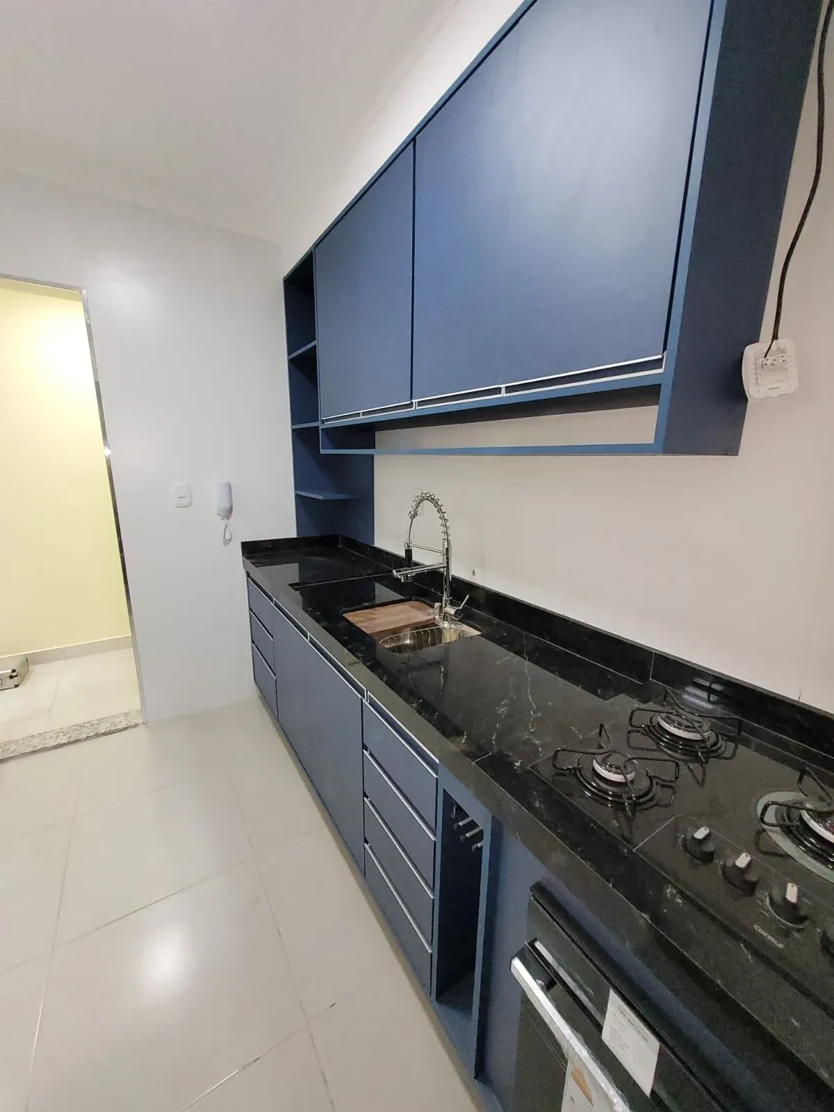 Cozinha corredor com armários azuis e bancada de granito preto